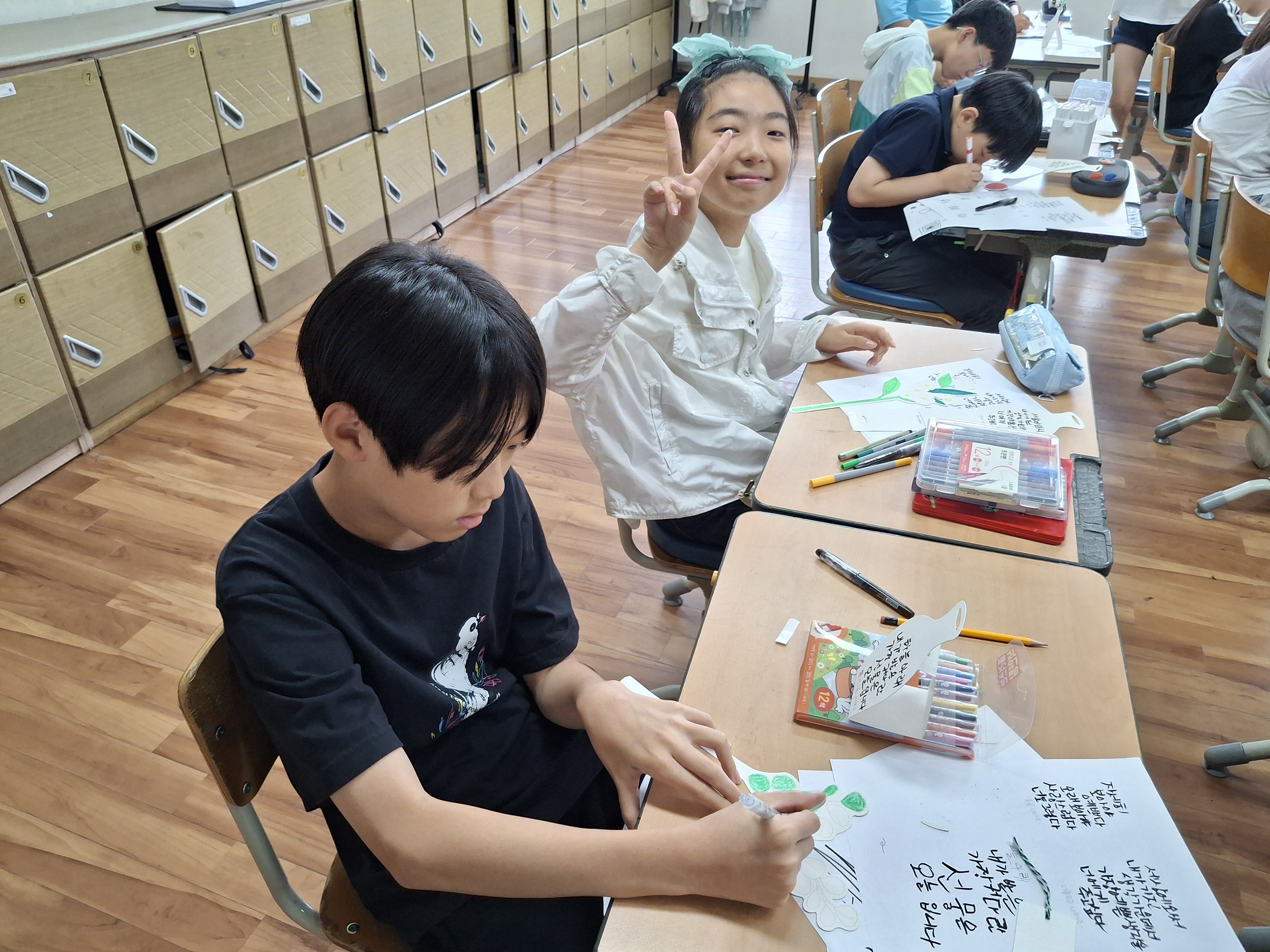 2. 마음에 와닿는 시 구절을 정성껏 써 내려가며 친구와 함께 밝은 미소로 브이를 그려요.
